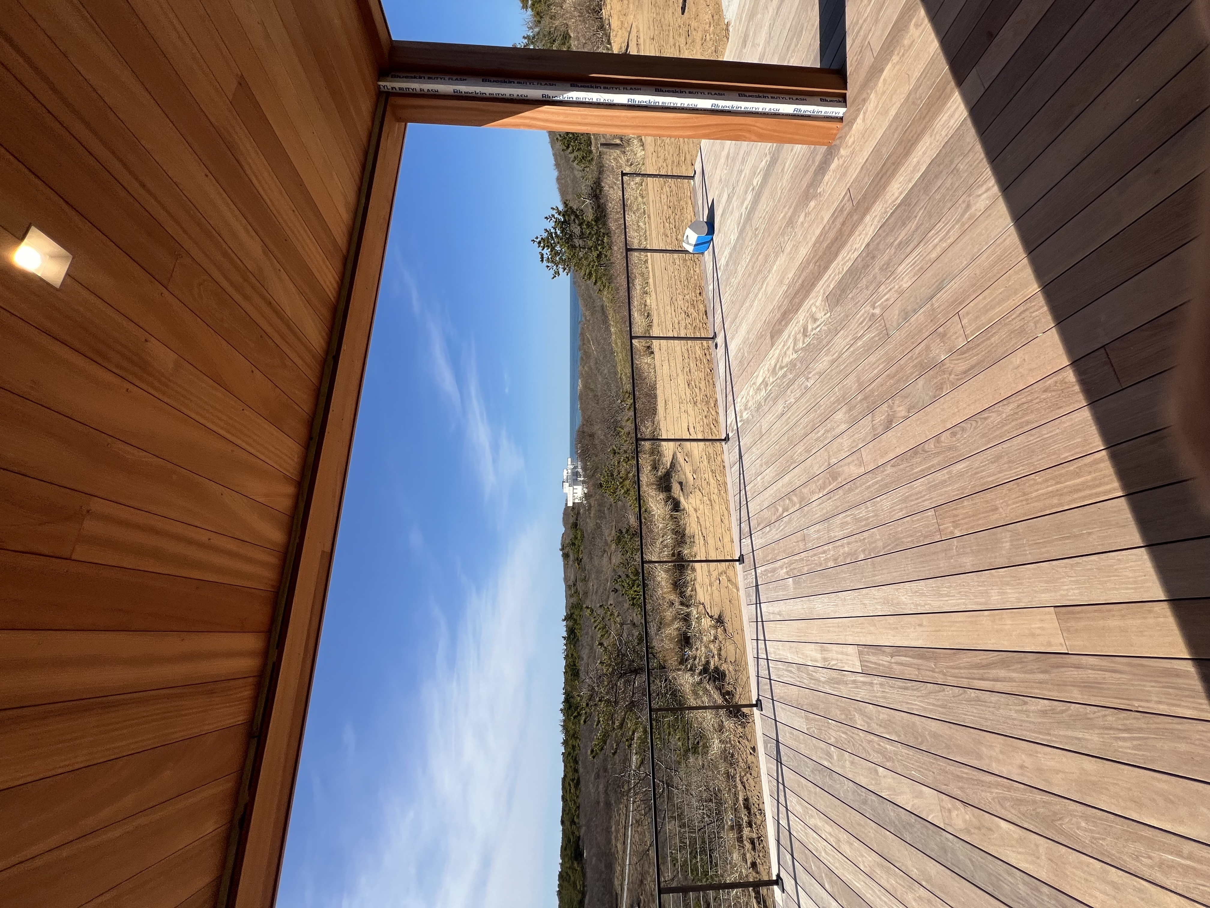 Covered deck with wood ceiling, railings, and ocean view.