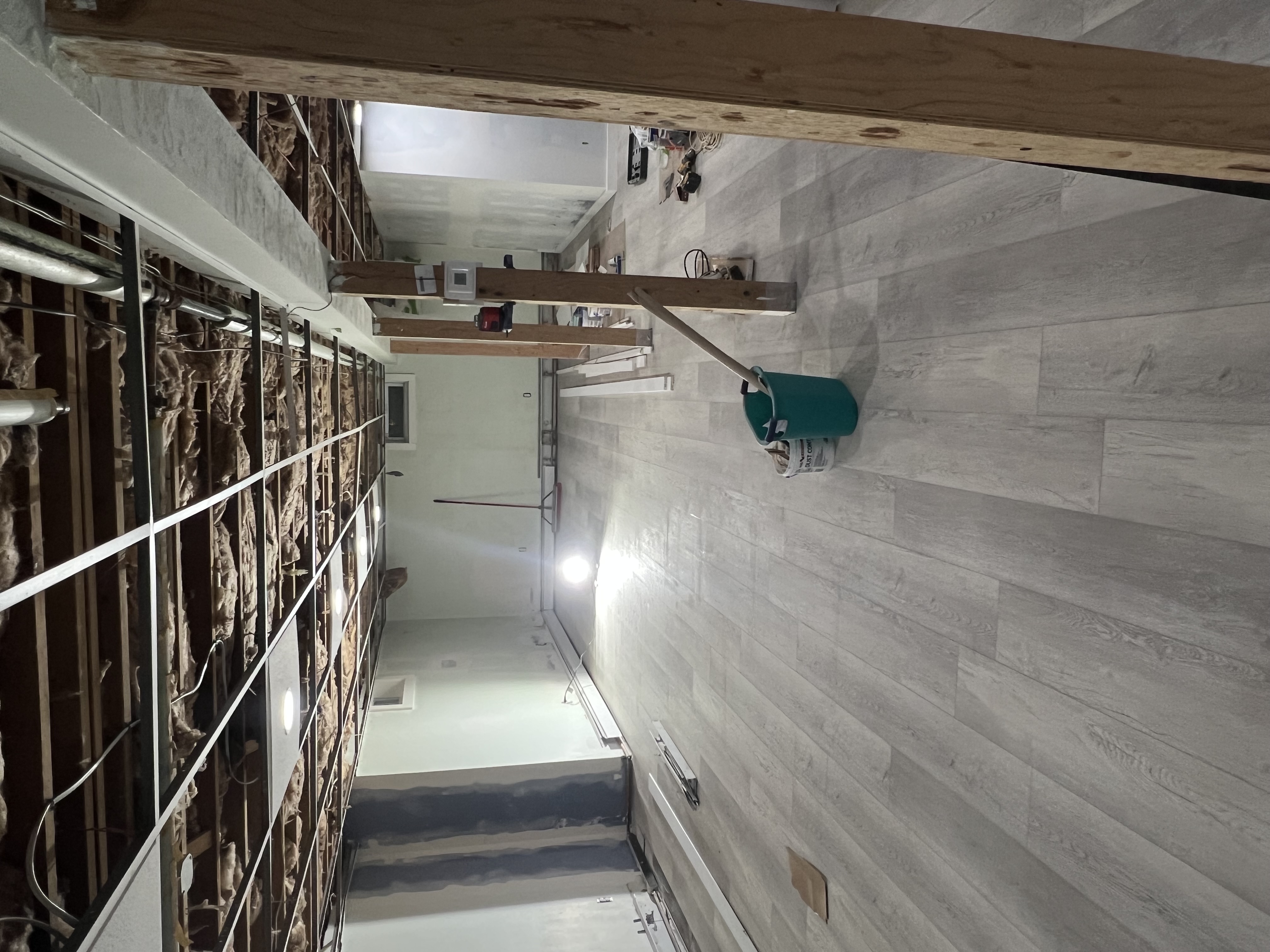 Basement renovation in progress with flooring installed and open ceiling grid.