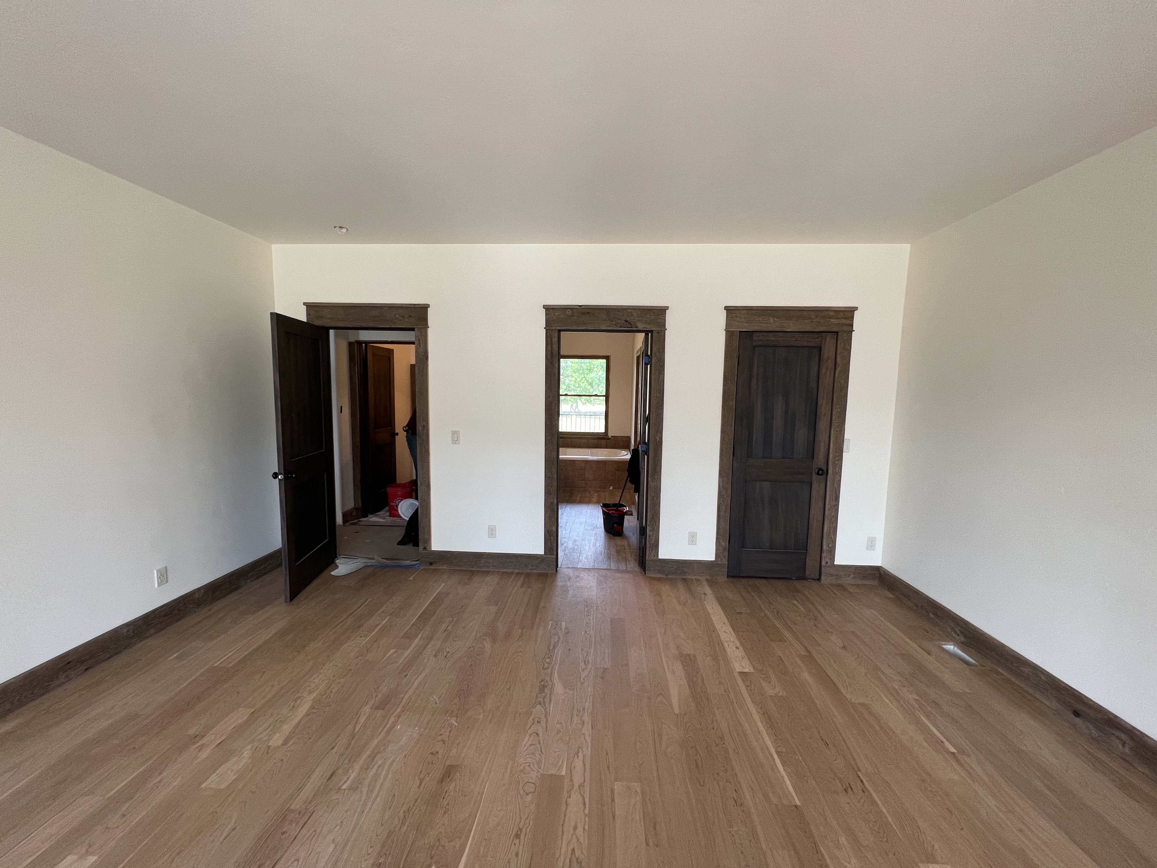 Finished room with wood flooring and dark stained trim around doors.